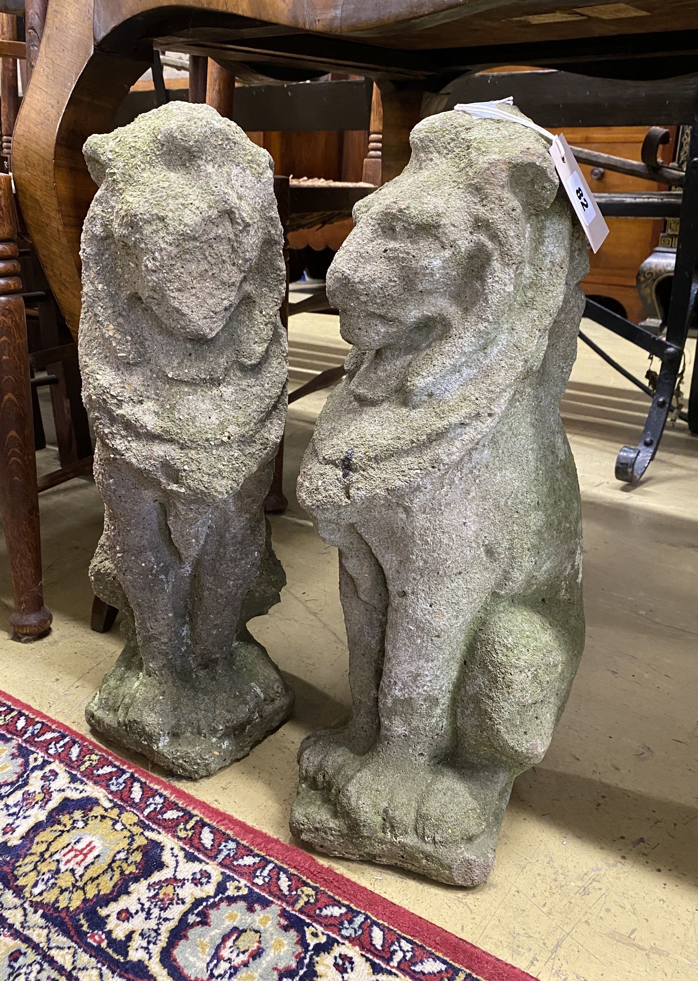 A pair of reconstituted stone seated lion garden ornaments, height 52cm